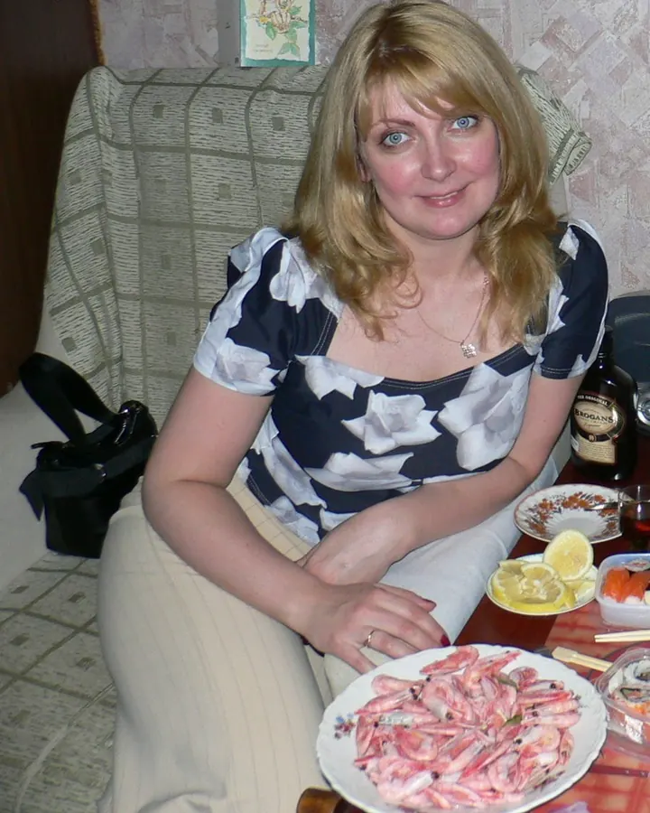 Femme blonde en top fleuri tenant une assiette de crevettes