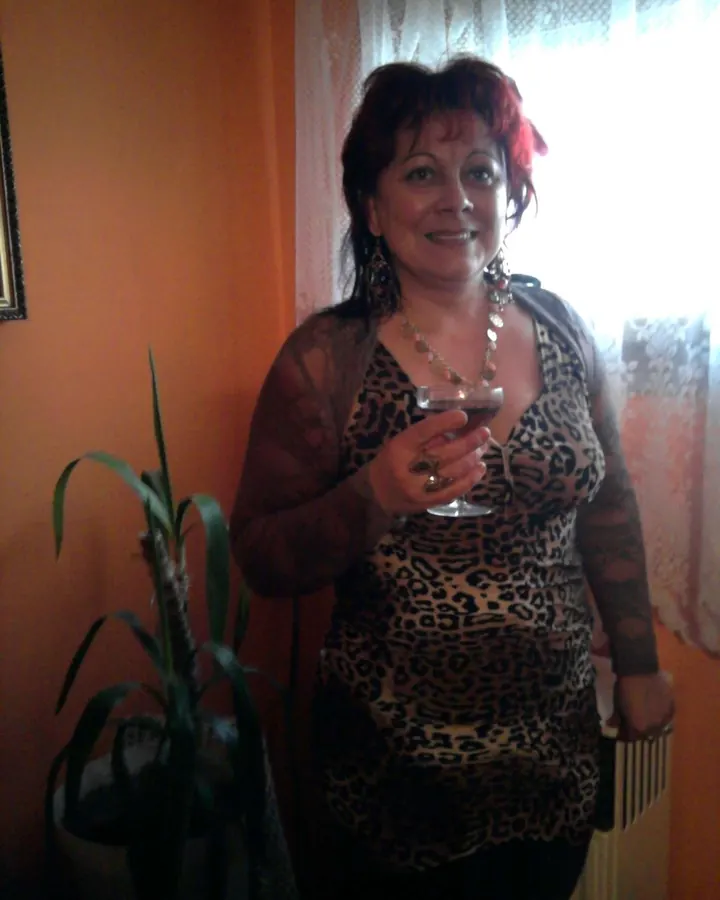 Femme rousse tenant un verre de vin devant un mur orange