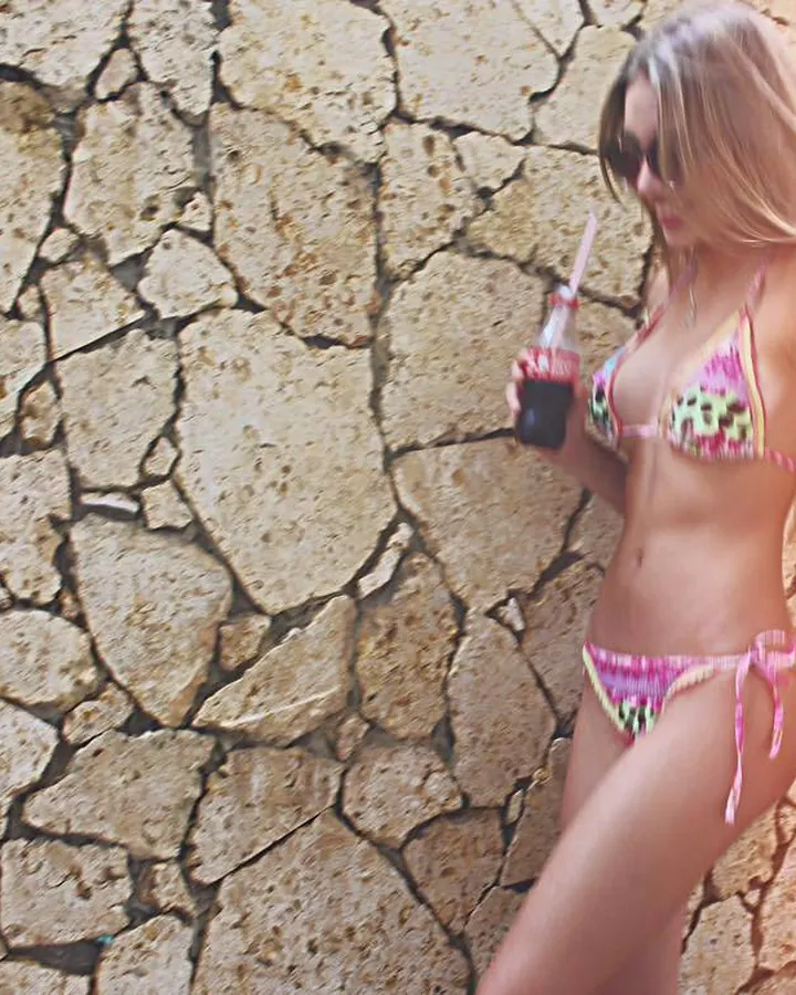 Jeune femme en maillot de bain tenant une bouteille de soda