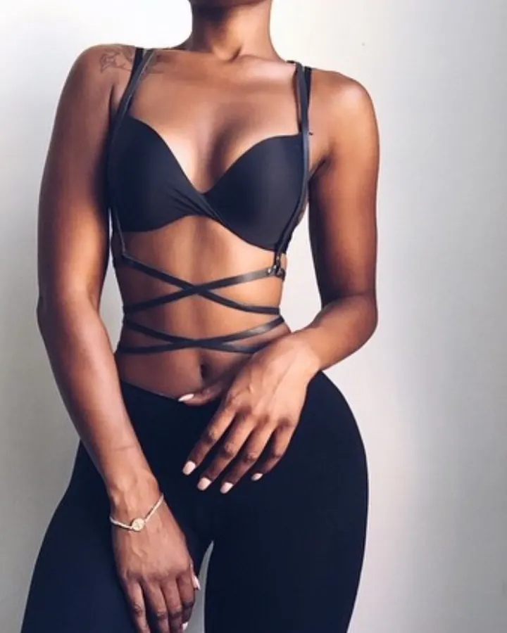 Femme aux cheveux bruns, regardant l'appareil photo, portant un haut noir et une jupe scintillante, assise dans une voiture.