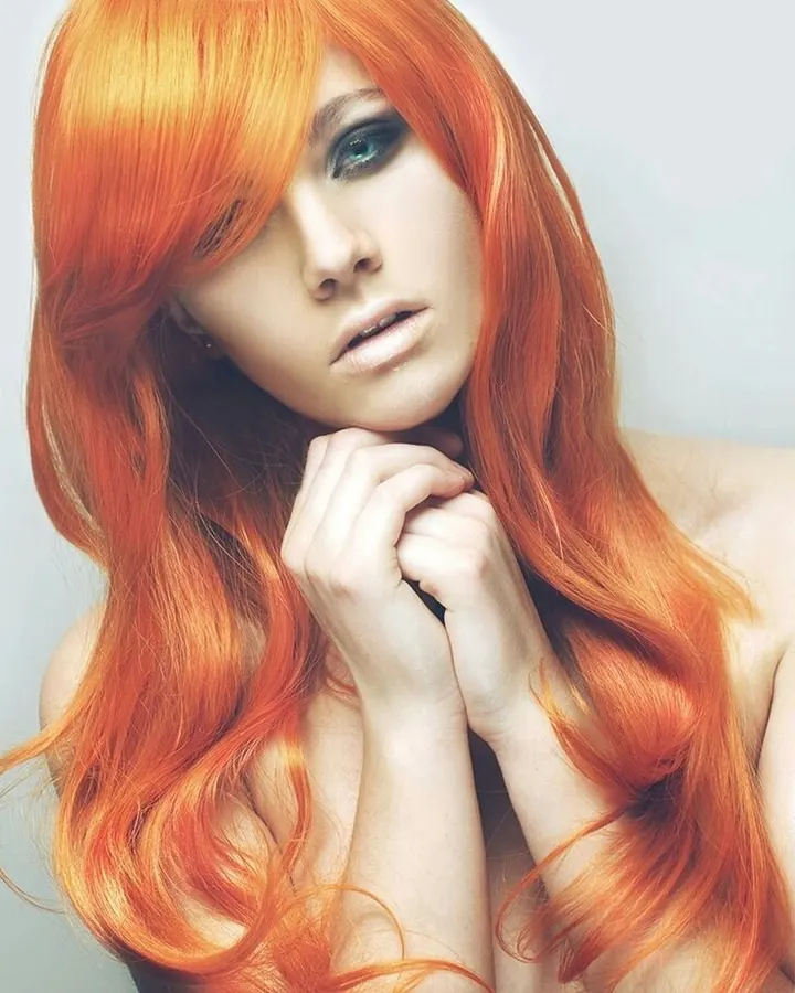 Femme aux cheveux roux portant un haut blanc, posant dans un intérieur avec des plantes