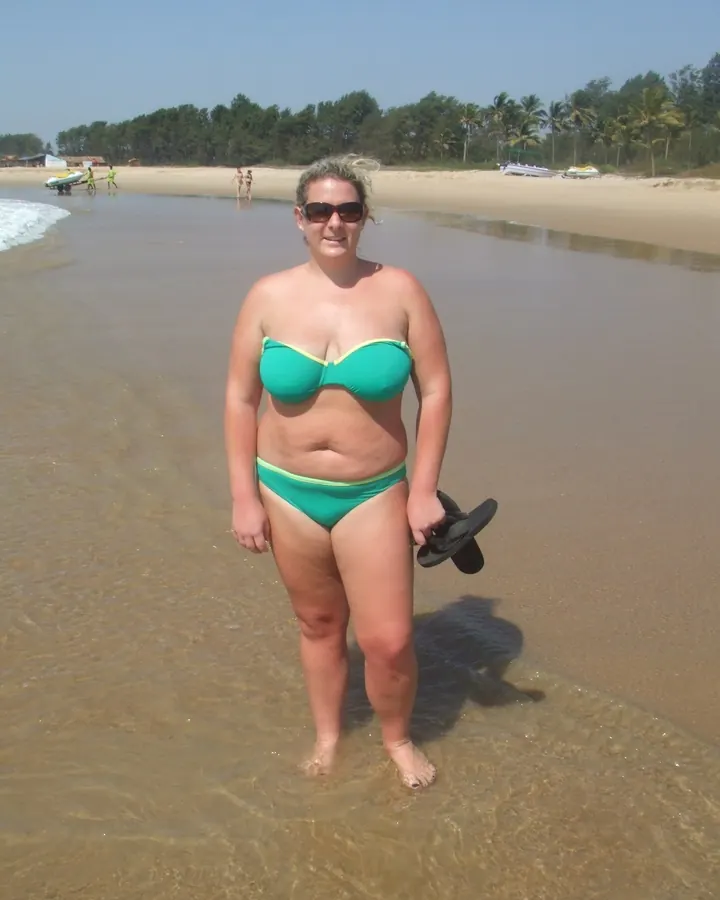 Femme en maillot de bain vert, debout dans l'eau à la plage