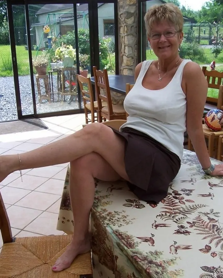 Sonia assise à une table de jardin en débardeur blanc