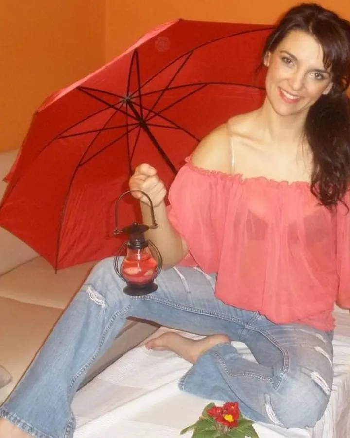 Femme en haut noir, assise sur un lit, regardant l'appareil photo avec un air séduisant