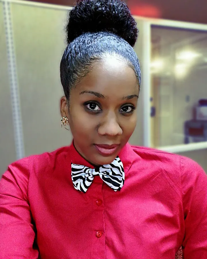 Femme aux cheveux noirs portant une chemise rouge et un nœud papillon zébré, souriant à l'appareil.