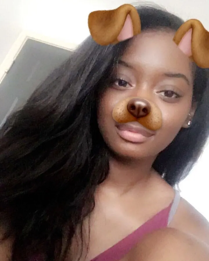 Femme aux cheveux noirs portant un débardeur rose, avec un filtre de chien ajouté à son visage, regardant directement l'appareil.