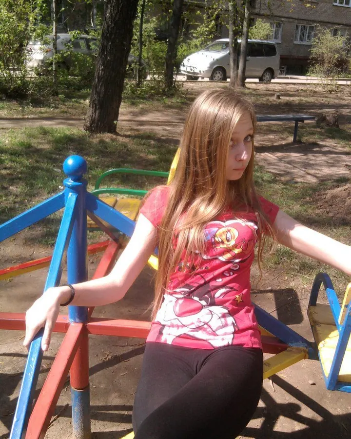 Jeune femme blonde assise sur un jouet coloré dans un parc, regardant l'appareil photo