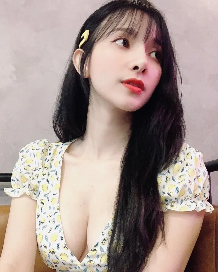 Jeune femme asiatique en robe jaune, posant devant un fond gris