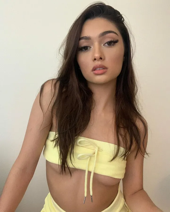 Jeune femme asiatique en haut jaune, regardant l'objectif avec un maquillage soigné.