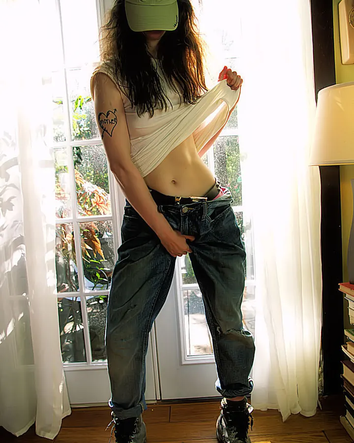 Femme trans aux cheveux châtains, en tenue noire, debout sur un escalier industriel