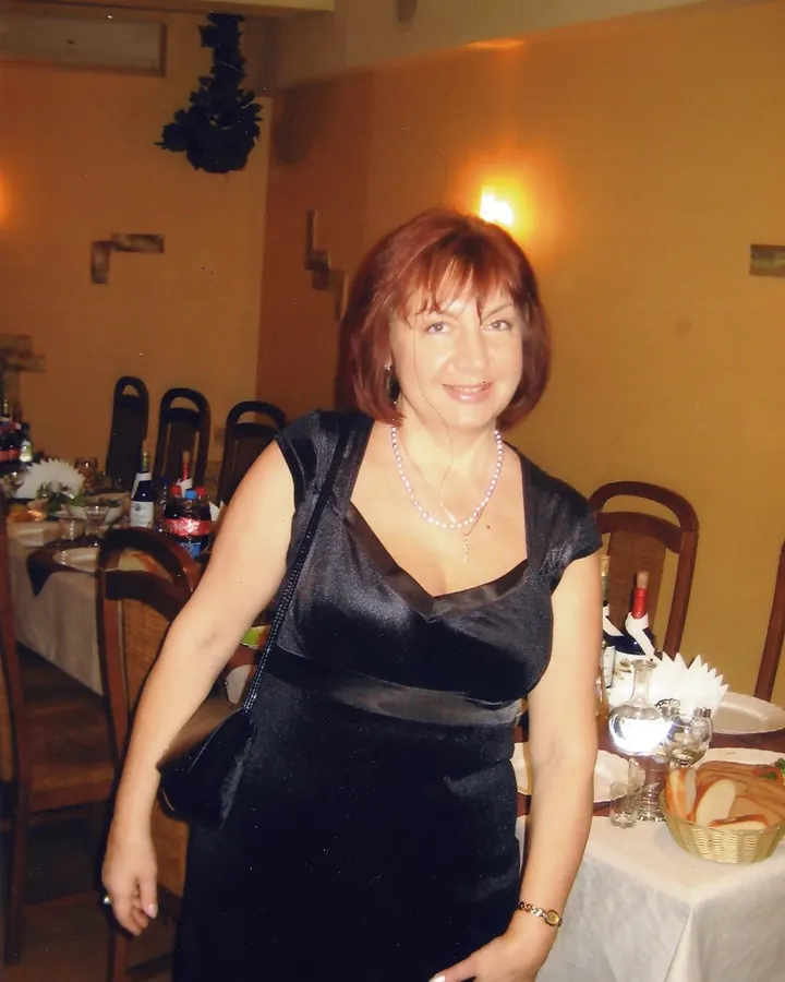 Femme blonde en robe noire, posant dans un couloir avec un tapis rouge