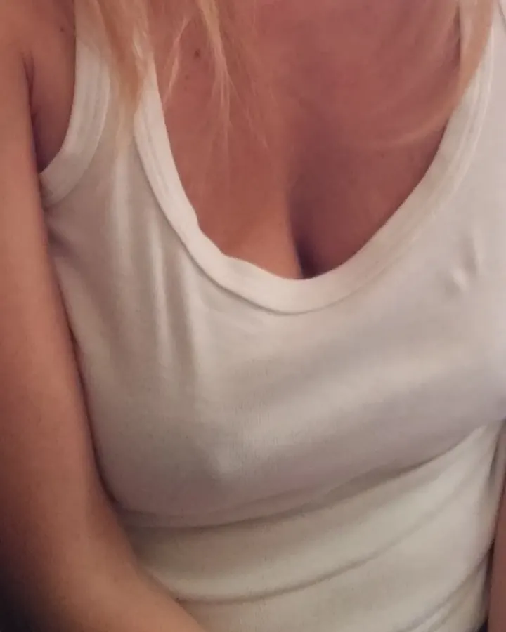 Femme blonde en débardeur blanc, vue du buste, assise