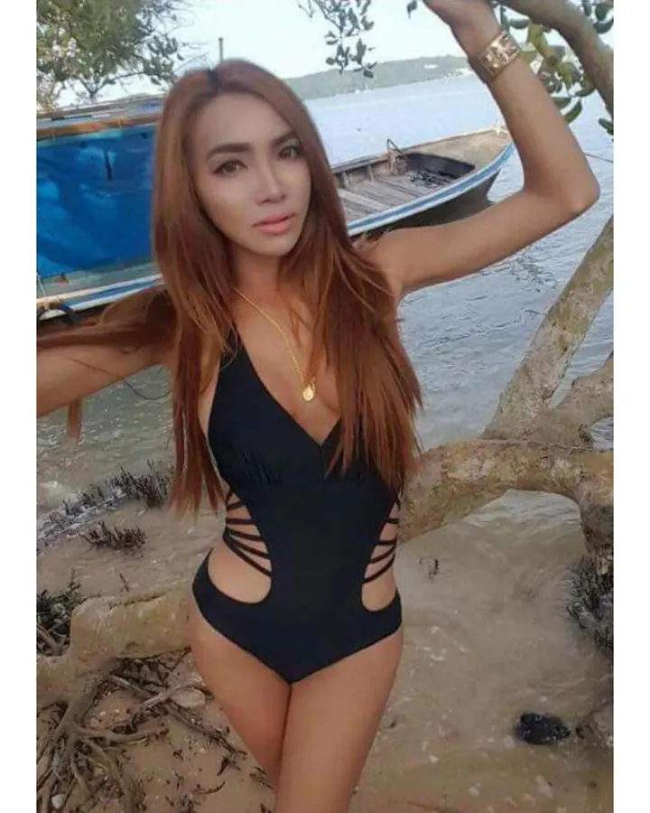 Femme en maillot de bain rose, allongée sur un matelas gonflable gris, près d’une piscine bleue, sous un soleil éclatant.